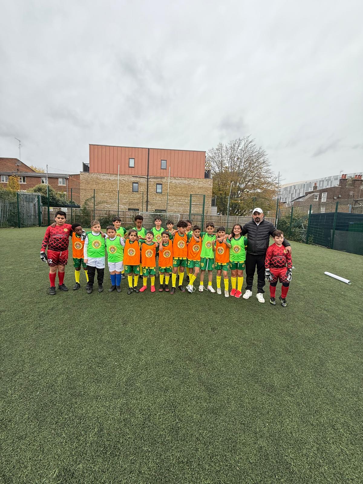Players lined up on the pitch, some wearing orange bibs